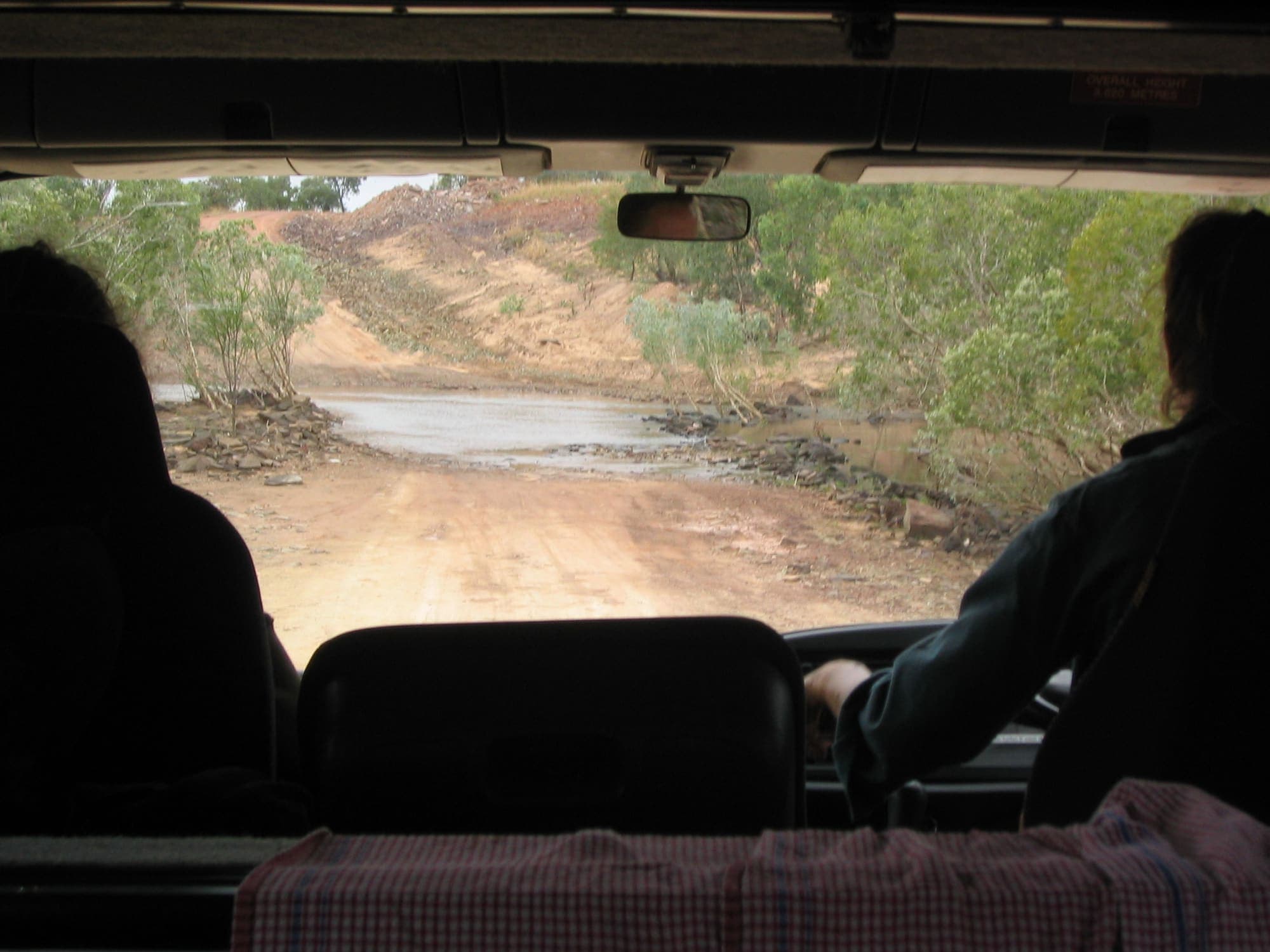 Unsealed red Gibb River Road stretching through open Kimberley woodland under a wide sky